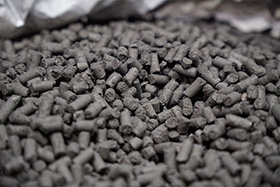 Close-up of a pile of dark coloured pellets.
