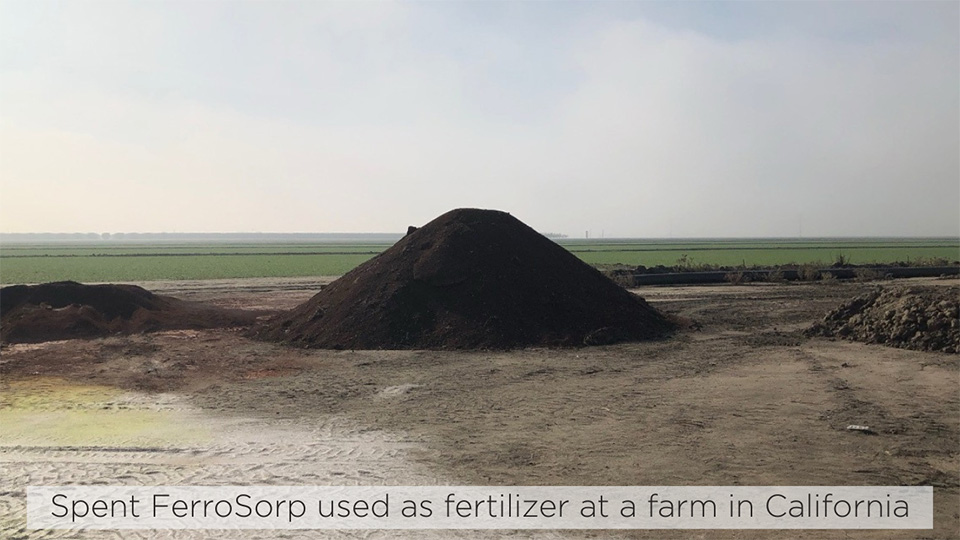 A large pile of dark, dirt-like substance, Spent FerroSorp used as fertilizer at a farm in California.